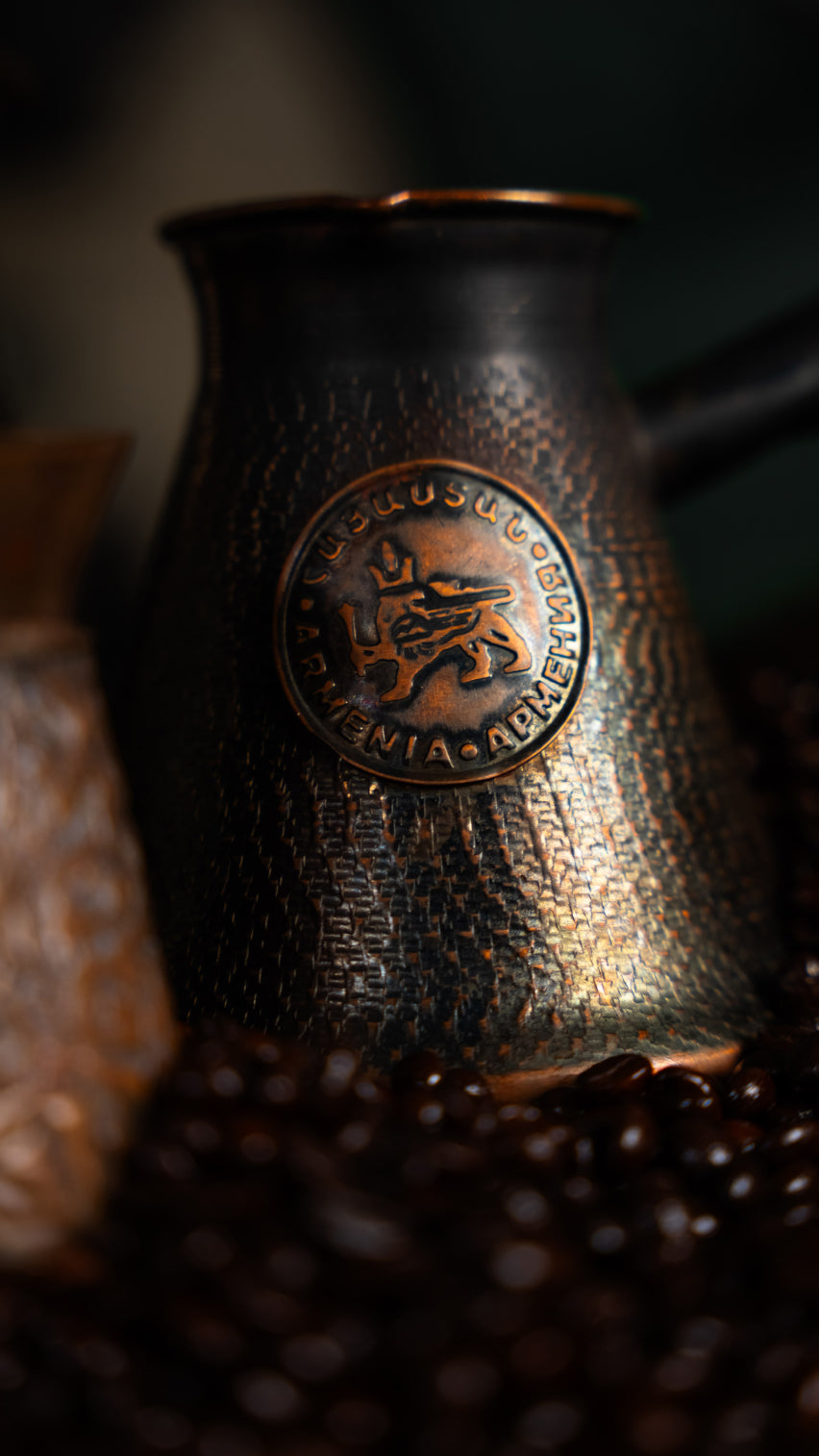 Traditional Armenian coffee pot (jazve) surrounded by roasted coffee beans.